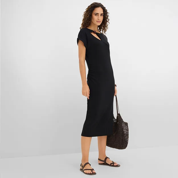 Elegante abito midi nero con scollo asimmetrico e borsetta nera abbinata.