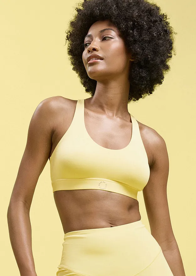 Una donna indossa un reggiseno sportivo giallo e dei pantaloni sportivi abbinati.