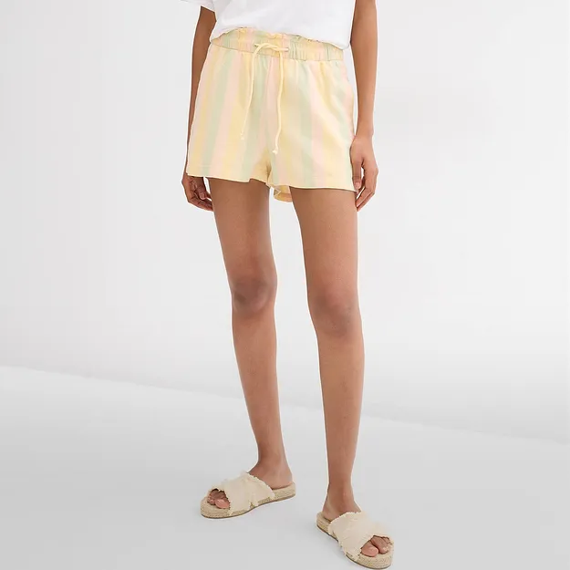 Pantaloncini a righe dai colori pastello, maglietta bianca e comodi sandali di rafia per le giornate calde.