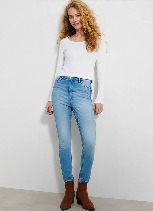 Semplice maglia bianca, jeans chiari e stivaletti marroni.