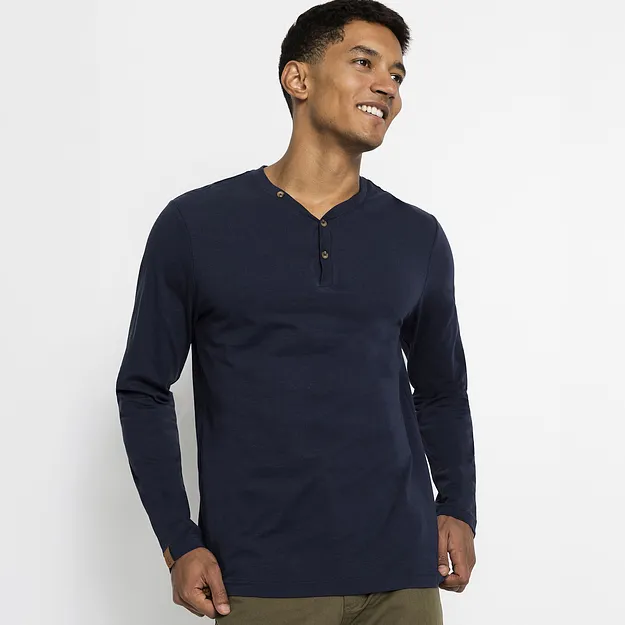 Un uomo indossa una maglietta a maniche lunghe blu scuro con abbottonatura e un paio di pantaloni verde oliva.