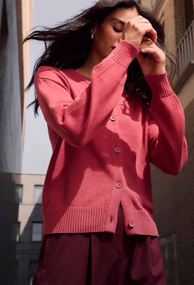 Cardigan color corallo brillante e dei pantaloni bordeaux.