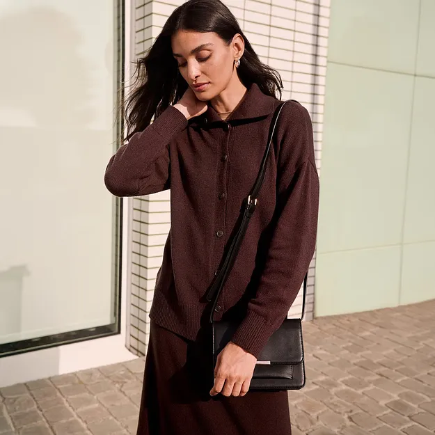 Elegante cardigan marrone con collo e abbottonatura, abbinato a una borsa nera.