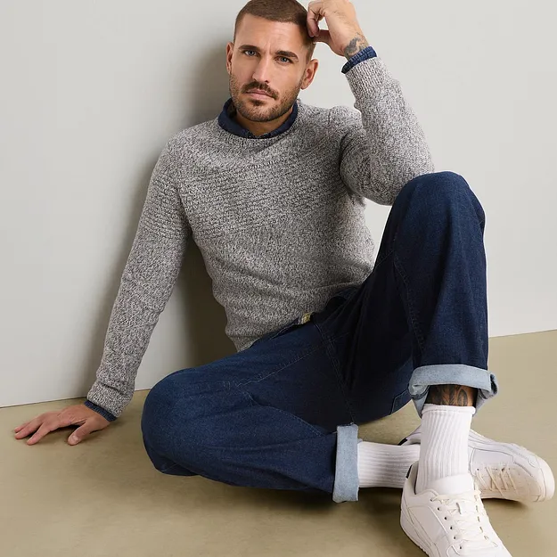 Maglione, camicia blu e jeans: un abbinamento disinvolto ed elegante.