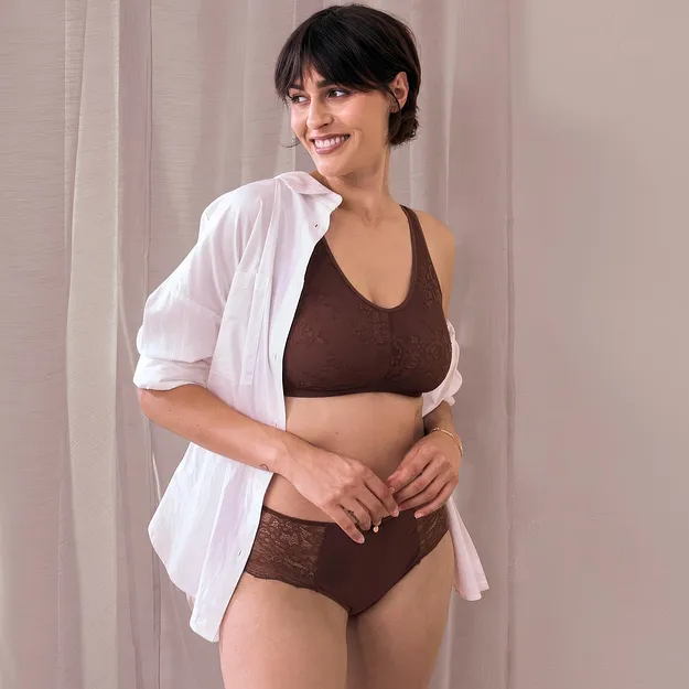 Camicia bianca aperta sopra un elegante completo intimo di pizzo marrone, composto da reggiseno e slip.