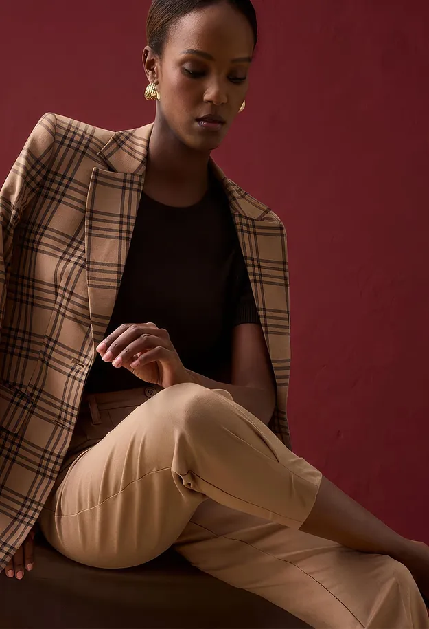Un blazer a quadri, un top scuro e pantaloni beige creano un outfit elegante.