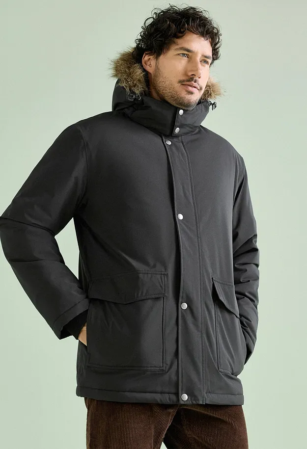 Un uomo indossa un parka nero con cappuccio di pelliccia