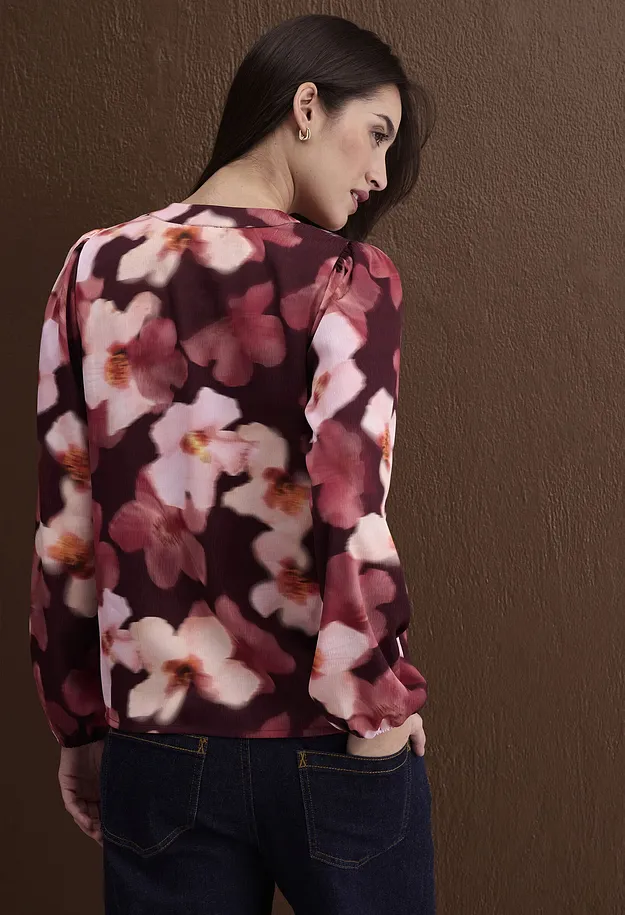 Camicetta a fiori rosso scuro con delicati motivi floreali, abbinata a un classico paio di jeans blu.