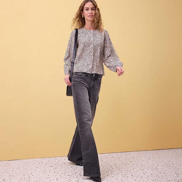 Camicetta leggera con motivi decorativi e maniche a sbuffo, abbinata a jeans grigi svasati.