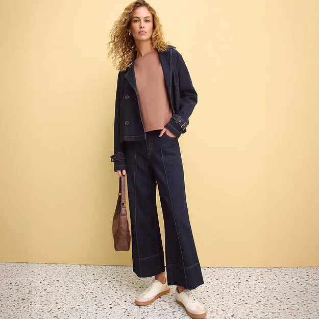 Elegante abbinamento di giacca di jeans scura, pantaloni larghi e maglione rosa. 