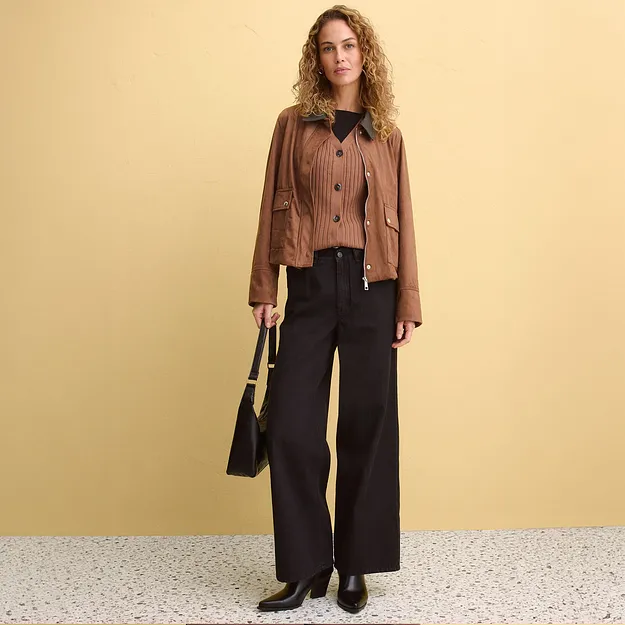 Elegante combinazione di giacca in pelle marrone, camicetta a righe e pantaloni larghi neri.