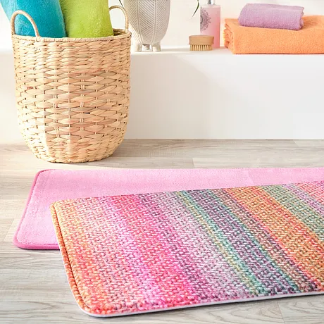 Asciugamani colorati e un tappetino da bagno vivace portano freschezza al bagno. 