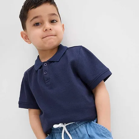 Una polo blu scura abbinata a dei jeans azzurri.