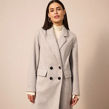 Cappotto grigio doppiopetto, abbinato a dolcevita color crema. 
