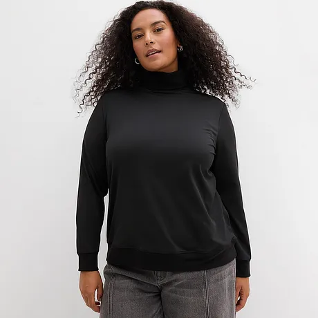 Maglia a collo alto nera con jeans grigi.