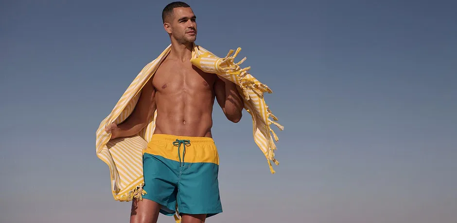 Beachwear per l'estate: pantaloncini da bagno gialli e turchesi con elastico in vita.