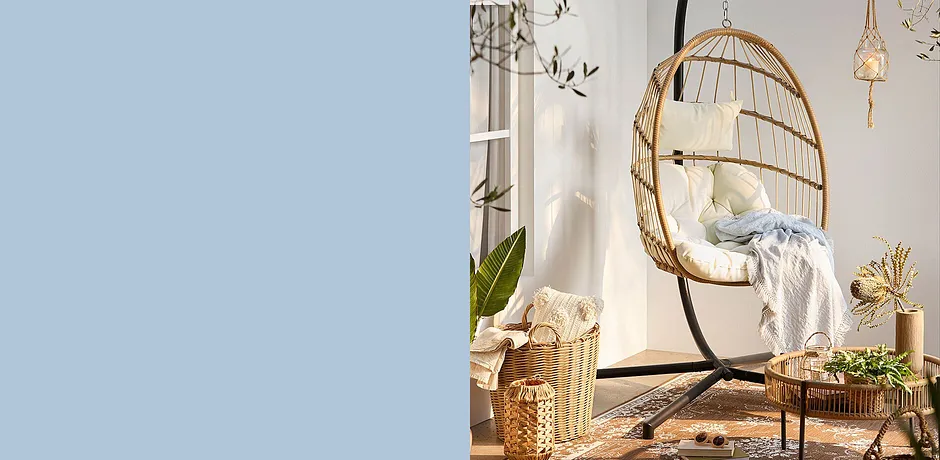 Poltrona sospesa accogliente in stile boho con morbidi cuscini e coperta soffice.