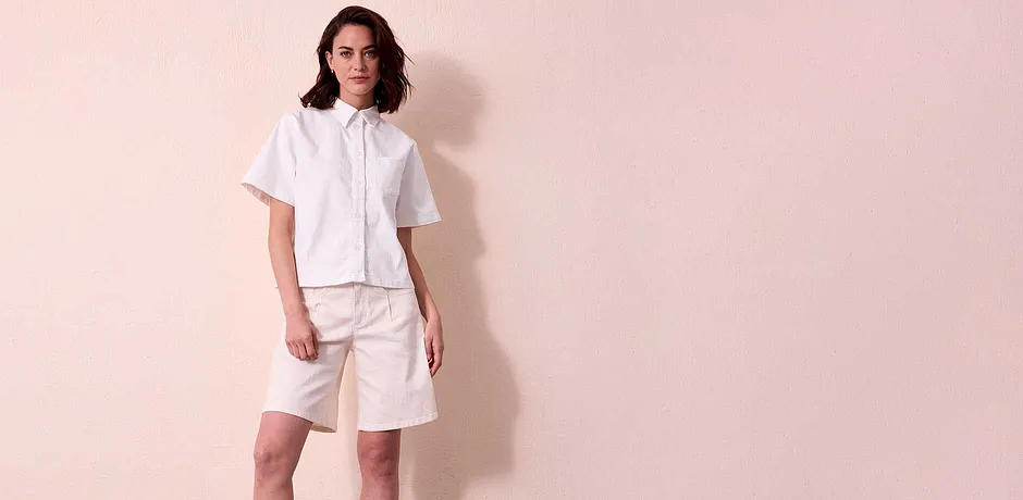 Outfit estivo in bianco: camicia di jeans a maniche corte con colletto e shorts al ginocchio.