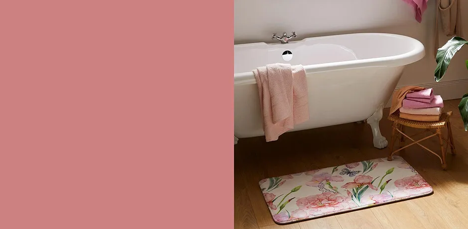 Asciugamani freschi e un tappetino da bagno floreale decorano il bagno con una vasca vintage bianca.