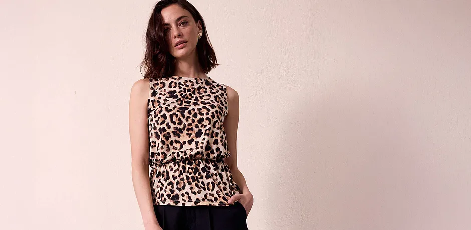Blusa senza maniche con stampa leopardata, elegante e raffinata. Pantaloni neri in contrasto con la stampa selvaggia. 