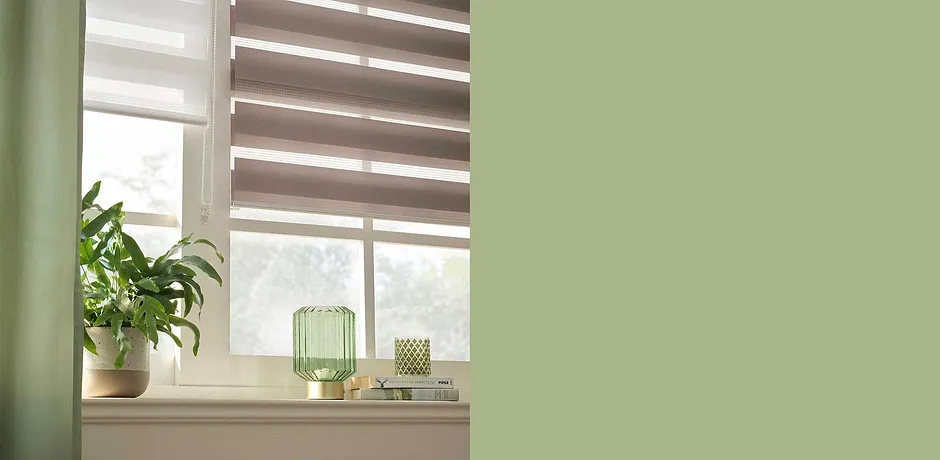 Decorazioni per finestre discrete con plissé in tonalità della terra. Decorazioni verdi e piante da interno conferiscono un'atmosfera naturale. 