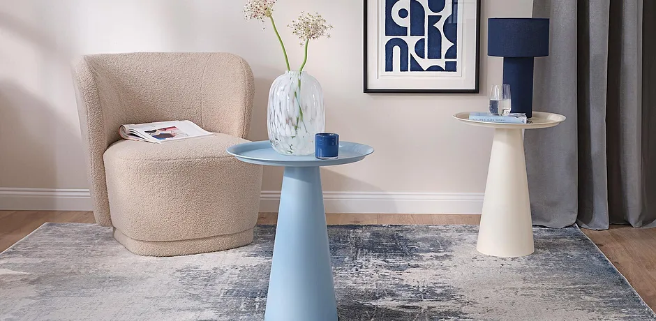 Salotto moderno con poltrona color crema e tavolino azzurro e beige.