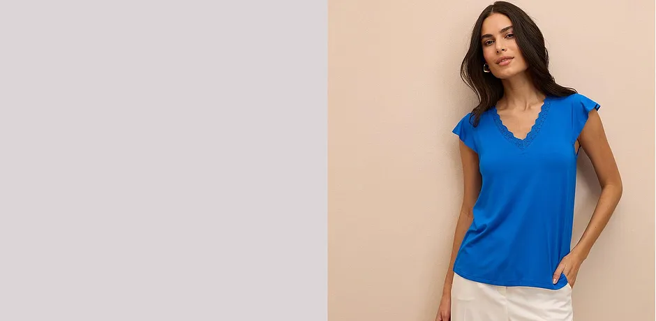 Top blu brillante con scollo a V e maniche corte, abbinato a pantaloni chiari.