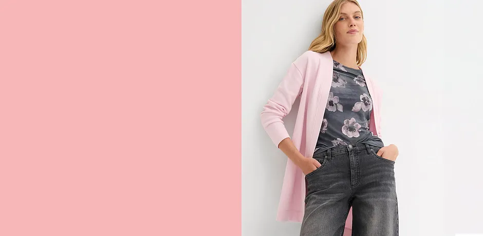 Cardigan lungo in felpa rosa su jeans scuri. Elegante contrasto tra tonalità chiare e scure.