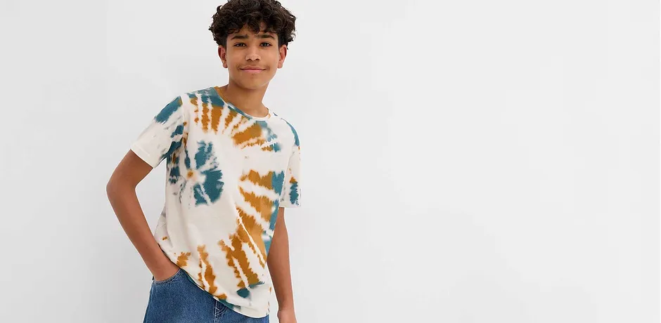 Moderna T-shirt batik in blu e arancione, abbinata a jeans classici per un look casual.
