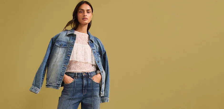 Look denim casual con giacca di jeans, camicetta chiara in pizzo e jeans a vita alta per uno stile moderno.
