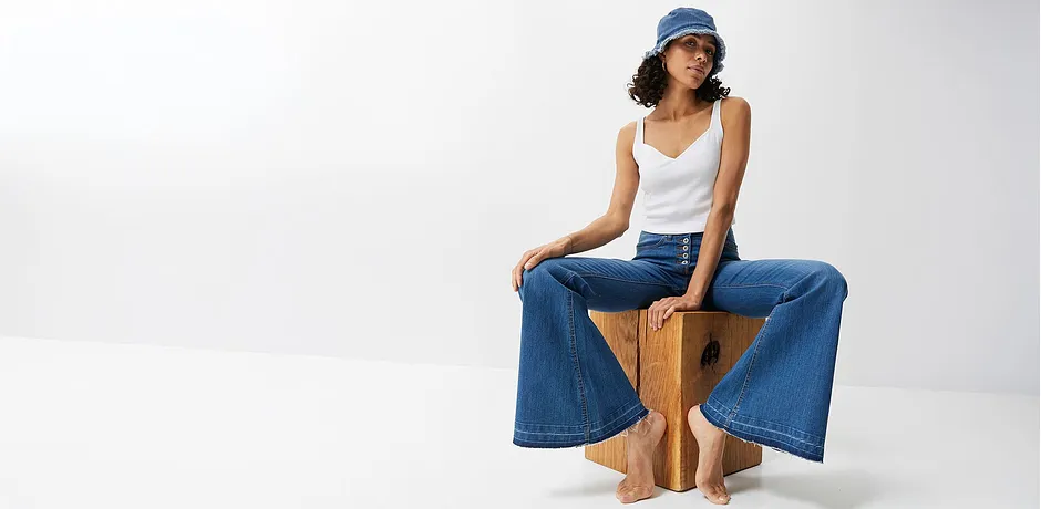 Jeans ampi, top bianco e cappellino blu: look estivo casual per le giornate calde.