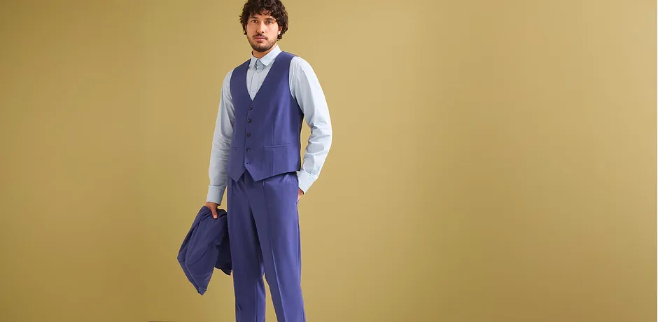 Completo da uomo blu con giacca, pantalone, gilet, abbinato a una camicia azzurra.
