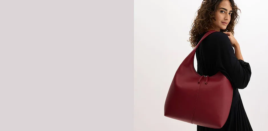 Maglione nero elegante abbinato a una borsa bordeaux.