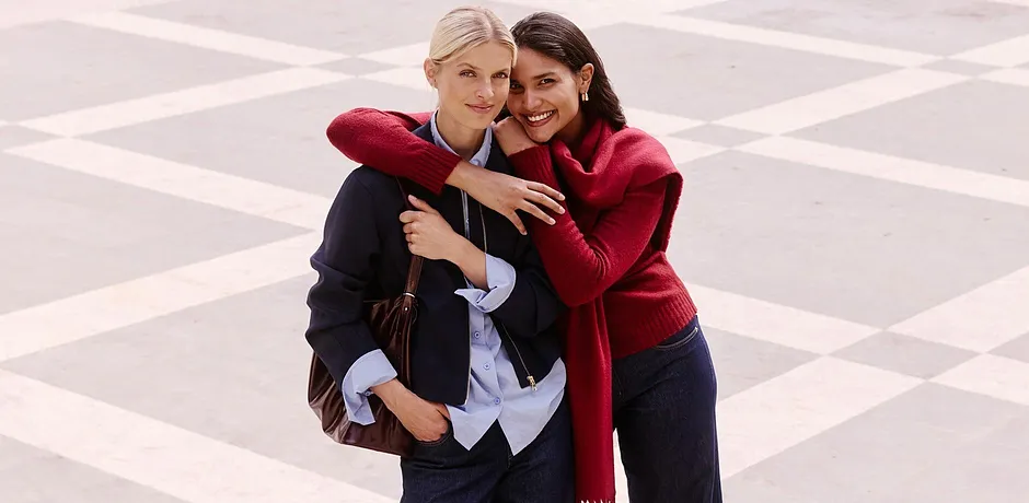 Donna con giacca e camicetta blu accanto a una donna con maglione e sciarpa rossi.