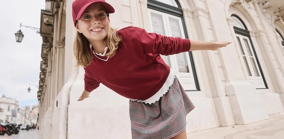 Maglione color borgogna abbinato a una gonna a quadri.