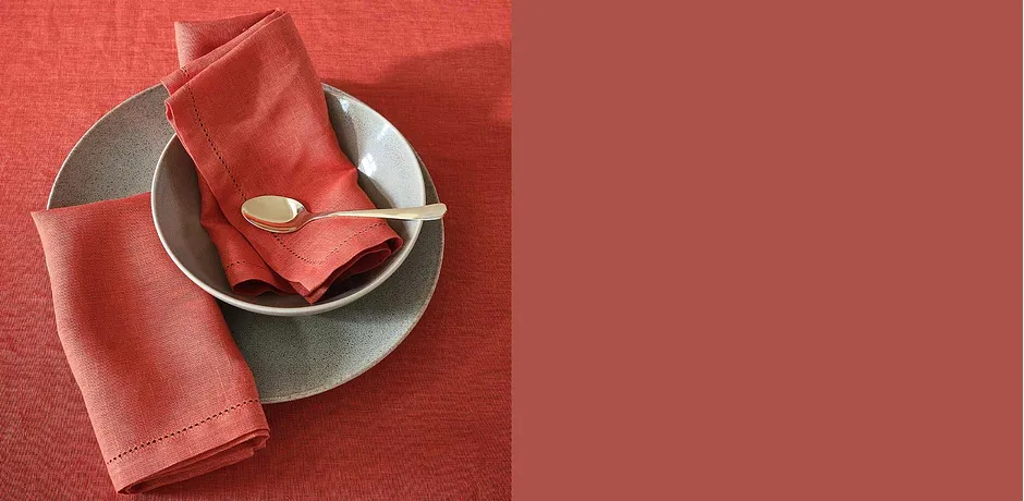 Decorazione da tavola in corallo: tovagliolo su piatto grigio con posate dorate.