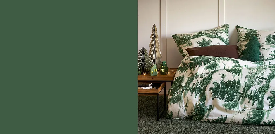 La biancheria da letto con motivo di abeti in verde e bianco decora l'accogliente camera da letto.