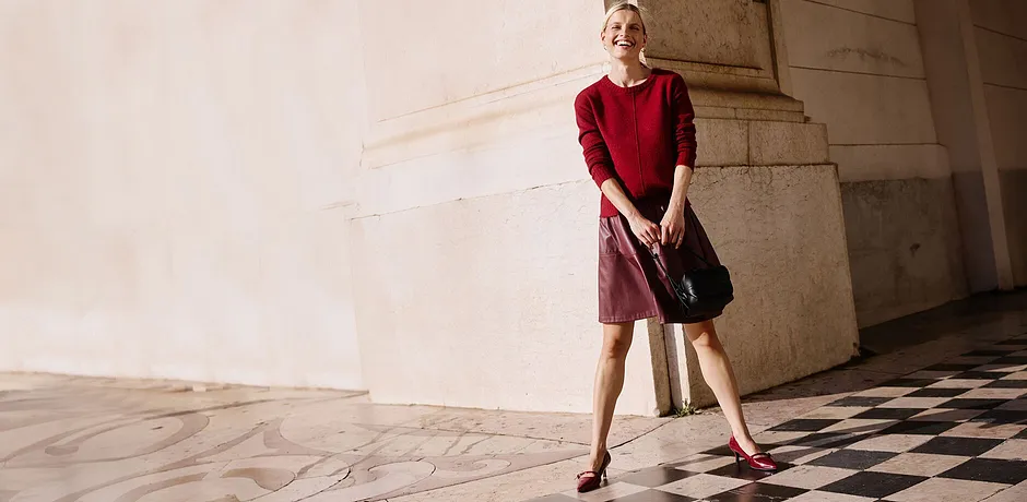 Maglione rosso e gonna corta rossa abbinati a borsa nera.