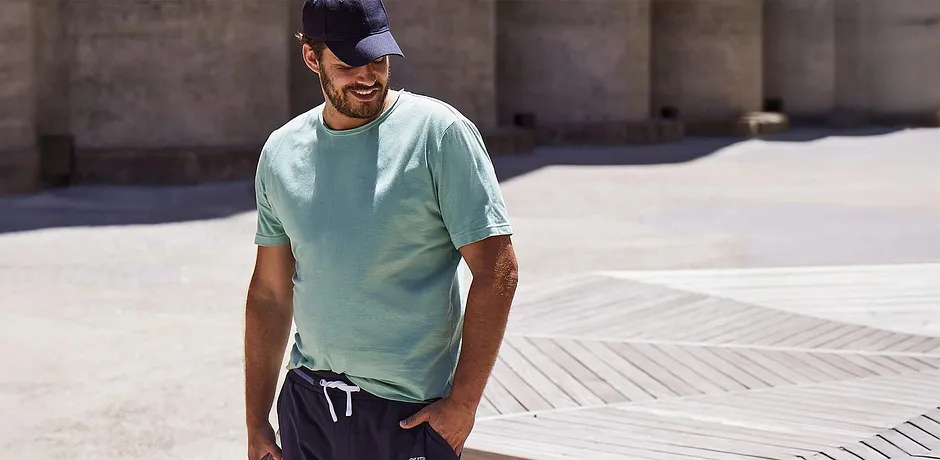 T-shirt turchese, pantaloni scuri e berretto.