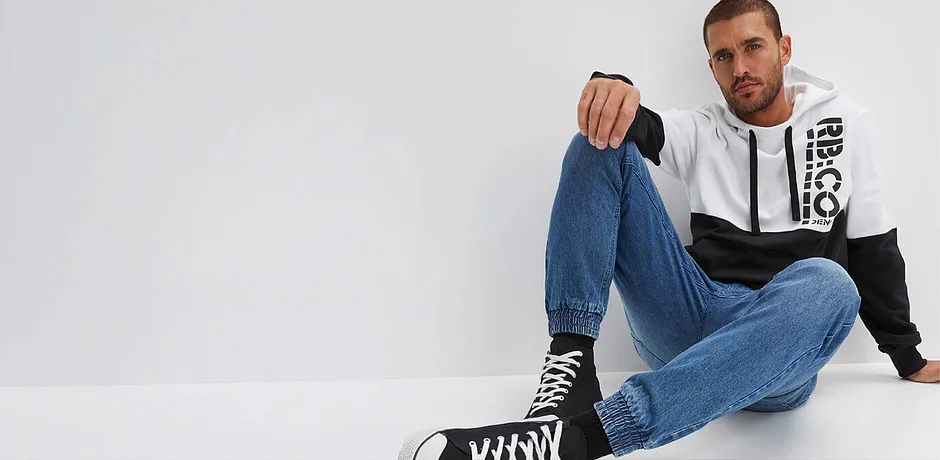 Look casual con jeans, felpa con cappuccio bicolore e sneaker alte. 