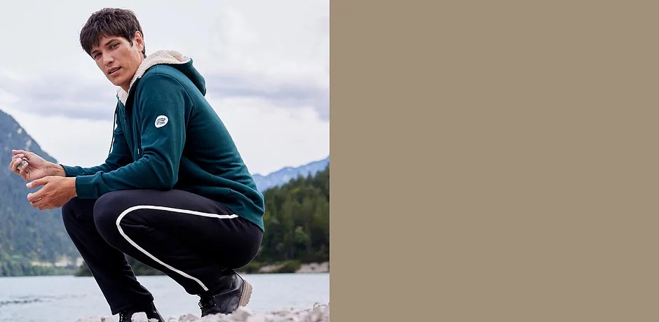 Giacca verde in felpa e pantaloni da jogging neri per attività all'aria aperta.