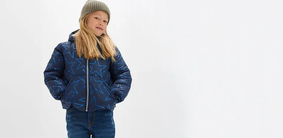 Giacca blu trapuntata, jeans e un morbido berretto verde.