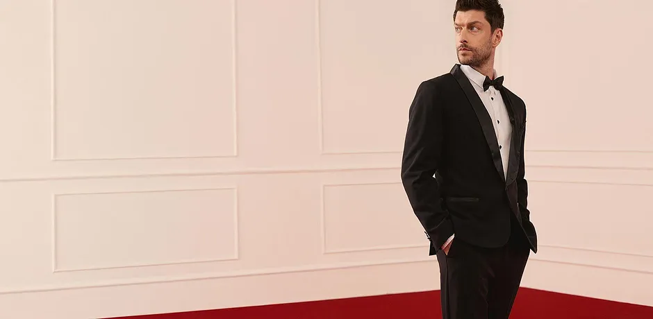 Elegante smoking nero con camicia bianca e papillon per occasioni speciali.