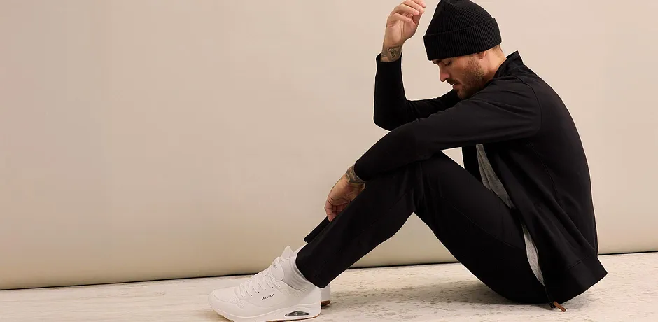 Tuta da jogging nera con cappuccio e scarpe da ginnastica bianche.