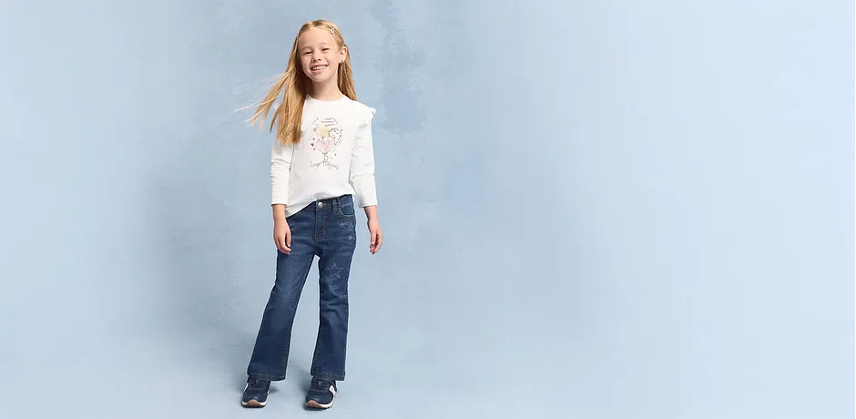 Look casual con maglietta bianca a maniche lunghe e jeans svasati. 