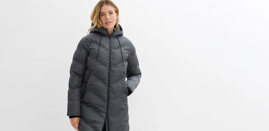 Giubbotto invernale lungo e grigio con cappuccio e cerniera.