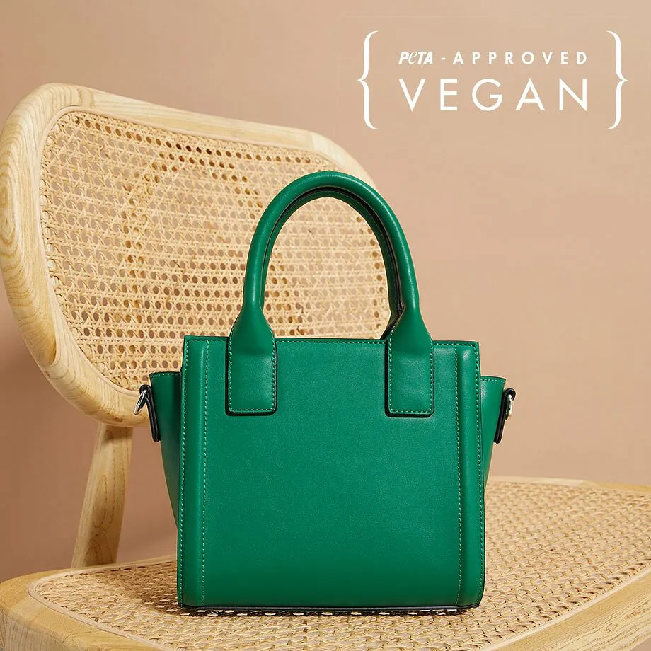Borsa a mano piccola in pelle vegana verde su una sedia in materiale naturale intrecciato.
