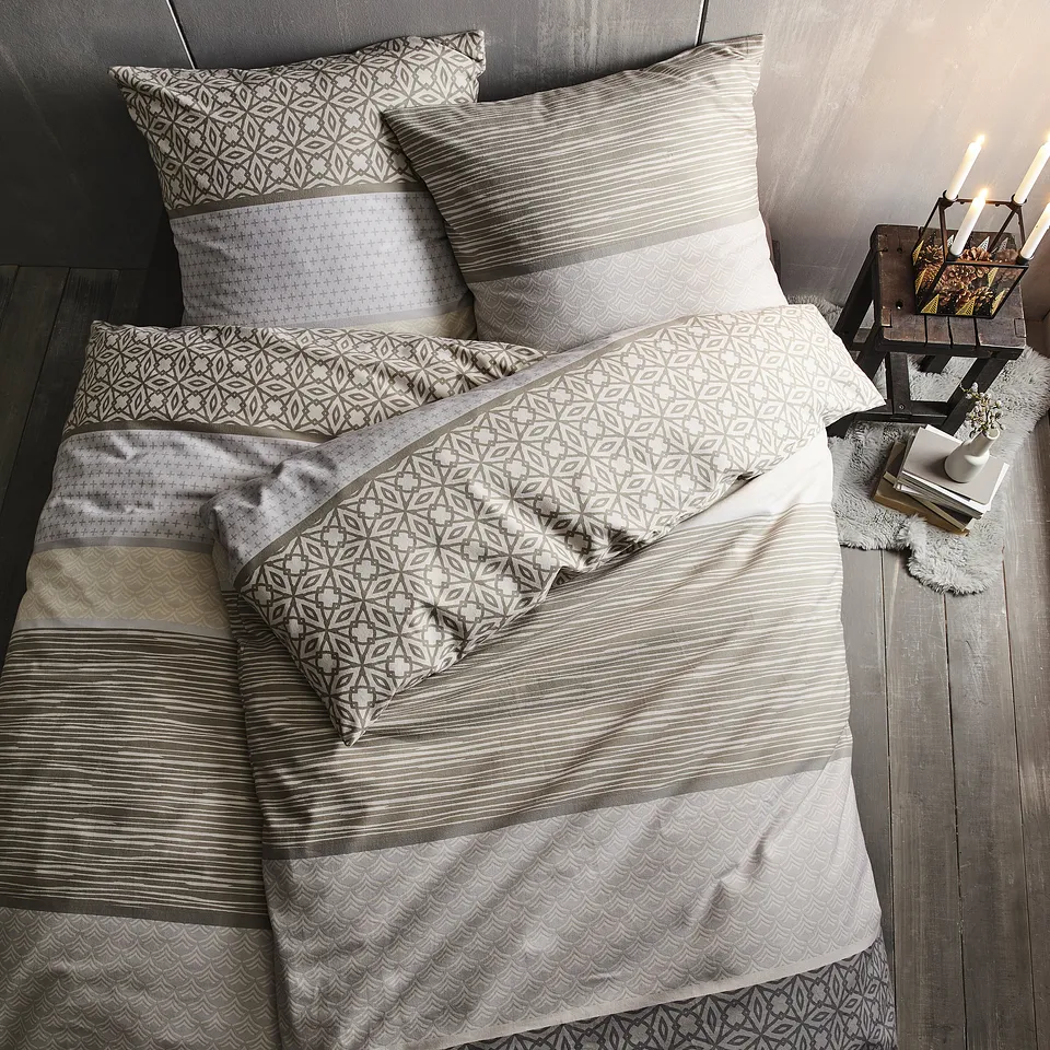 Biancheria da letto in tonalit&agrave; neutre con delicati motivi decorativi.