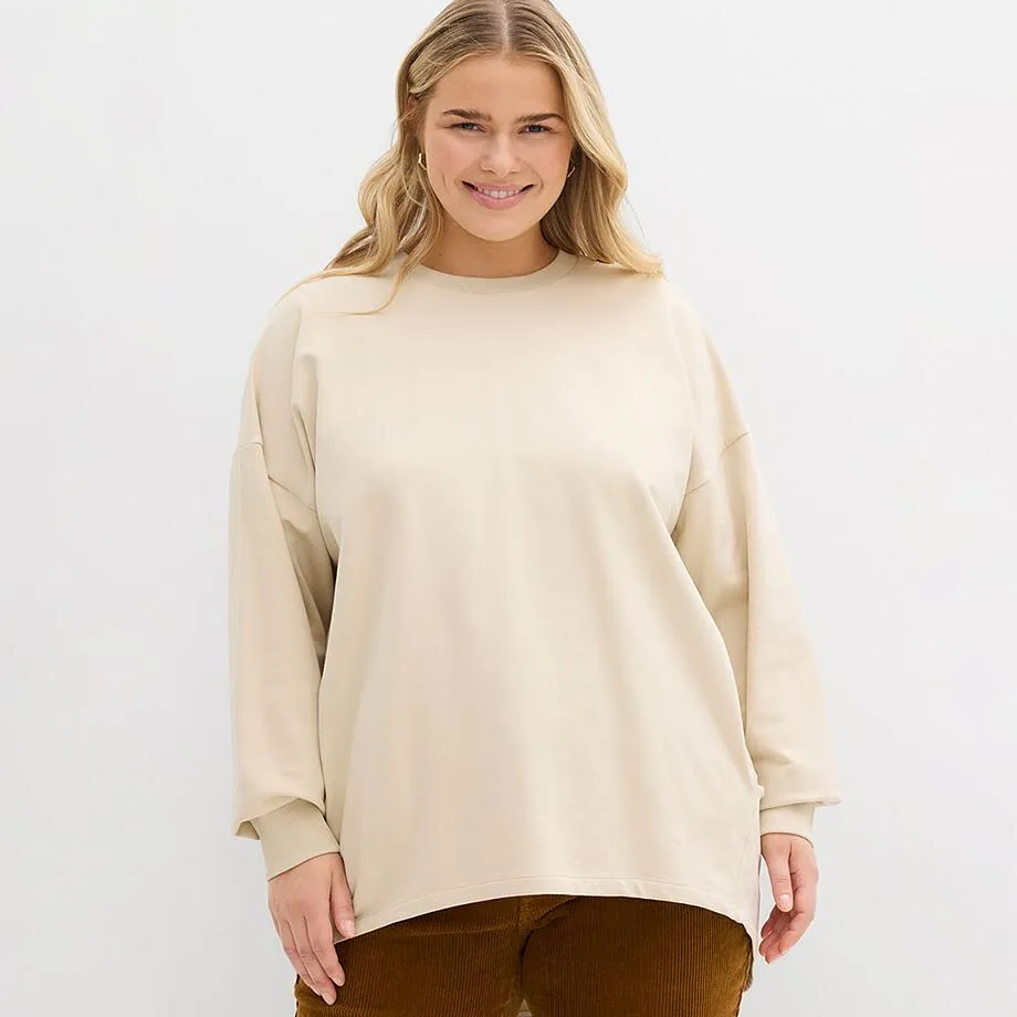 Felpa color crema con scollo rotondo, abbinata a pantaloni marroni.