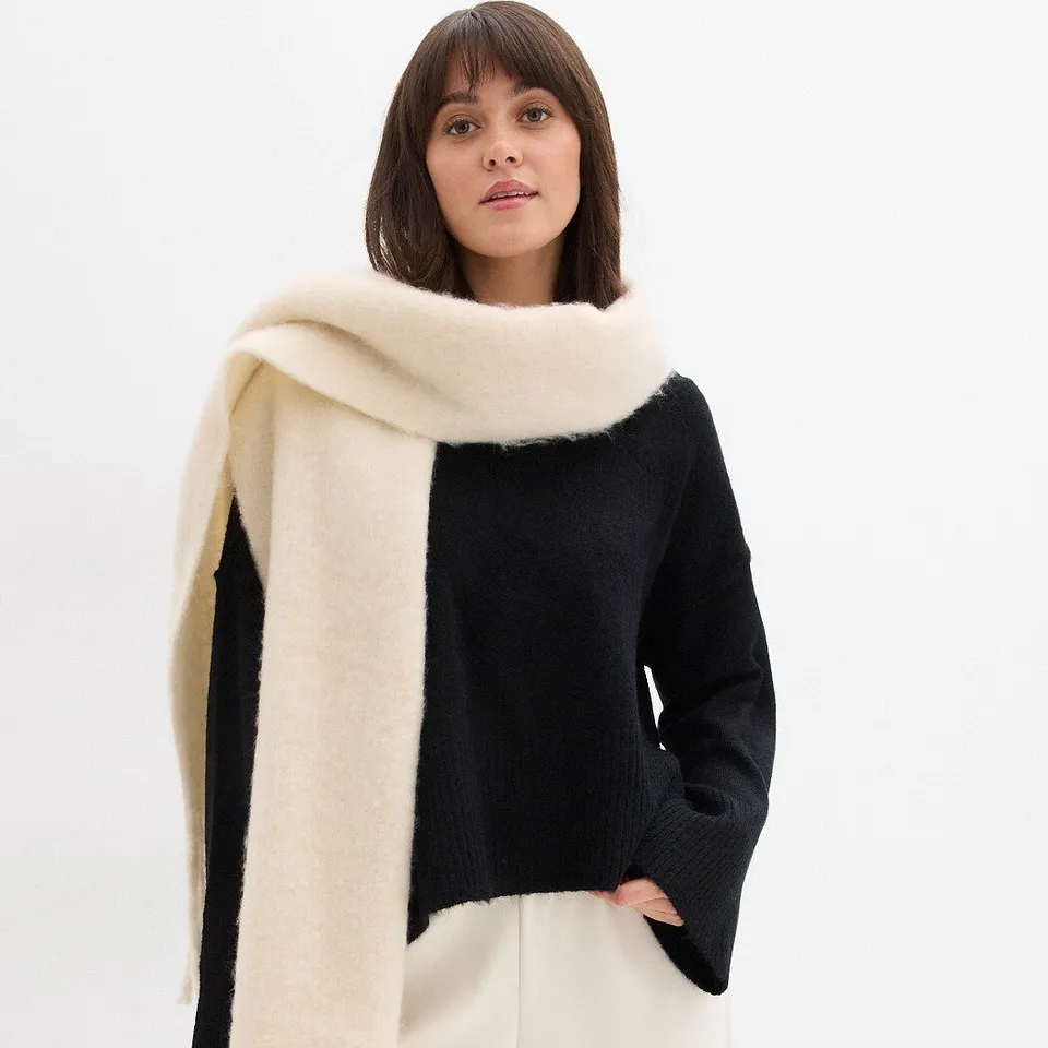 Maglione nero abbinato a una sciarpa color crema.